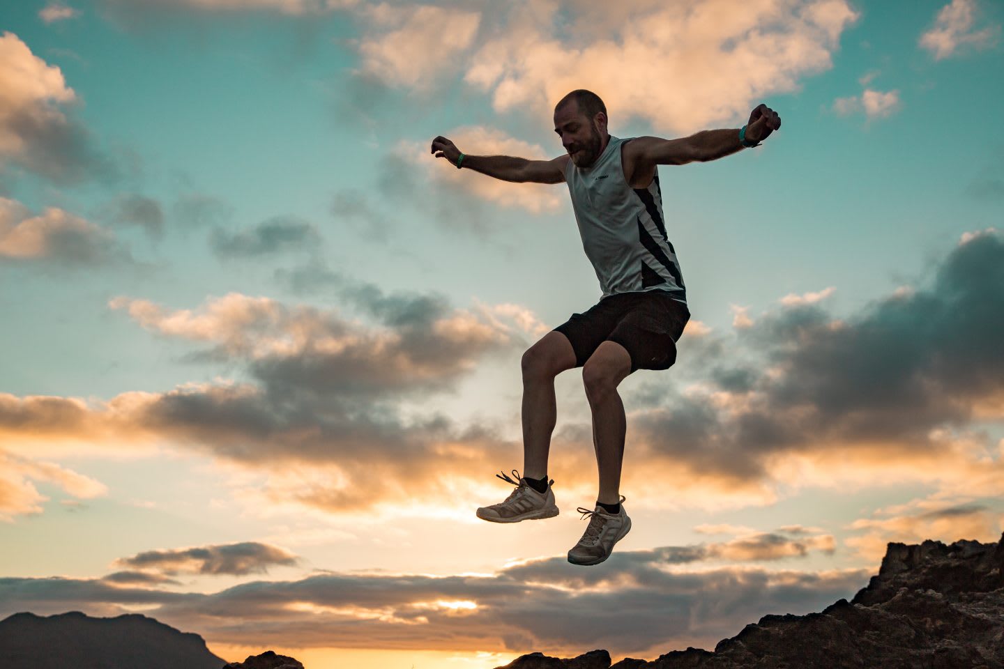 A man jumps for joy wearing running clothes in a sunset. running, sunset, joy, motivation, happy, concentration
