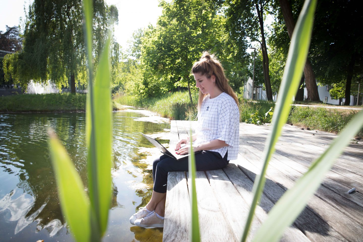 Woman working outside sitting on a land near a lake. adidas, GamePlan A, job, work life, lifestyle