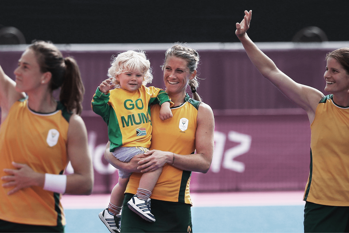 South African field hockey player Kate Woods is carrying her son on the pitch after a match.