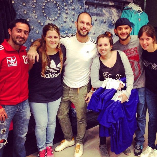 A group of people stand together holding clothes in a store opening in Chile. store, shopping, products, clothes