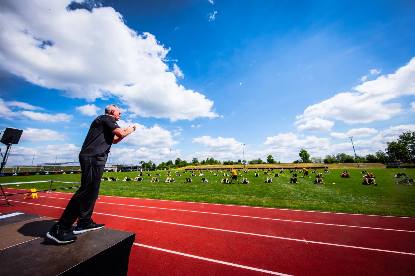 Mark Verstegen from the back standing on stage in a stadium and coaching a huge group of people during a workout. EXOS, adidas, leadership, leadership skills, leadership advice, interview, GamePlan A