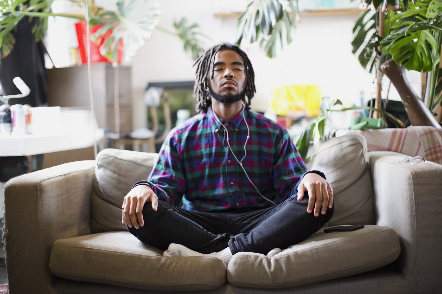 Serene young man listens to a podcast with headphones on apartment sofa | Listen to podcasts