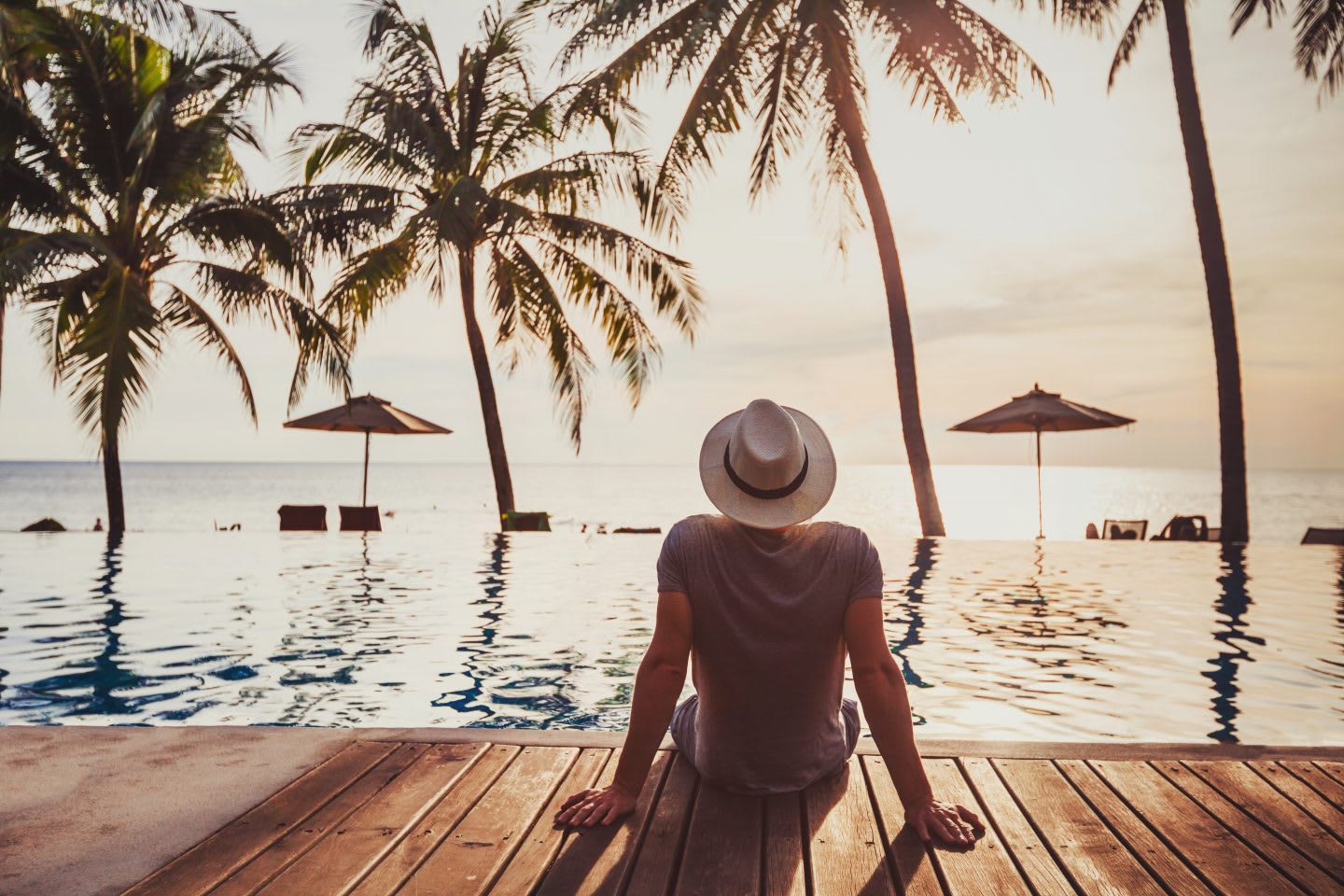 Man sitting at the pool and looking at the sea. habits and routines, improving productivity, healthy lifestyle, holiday season