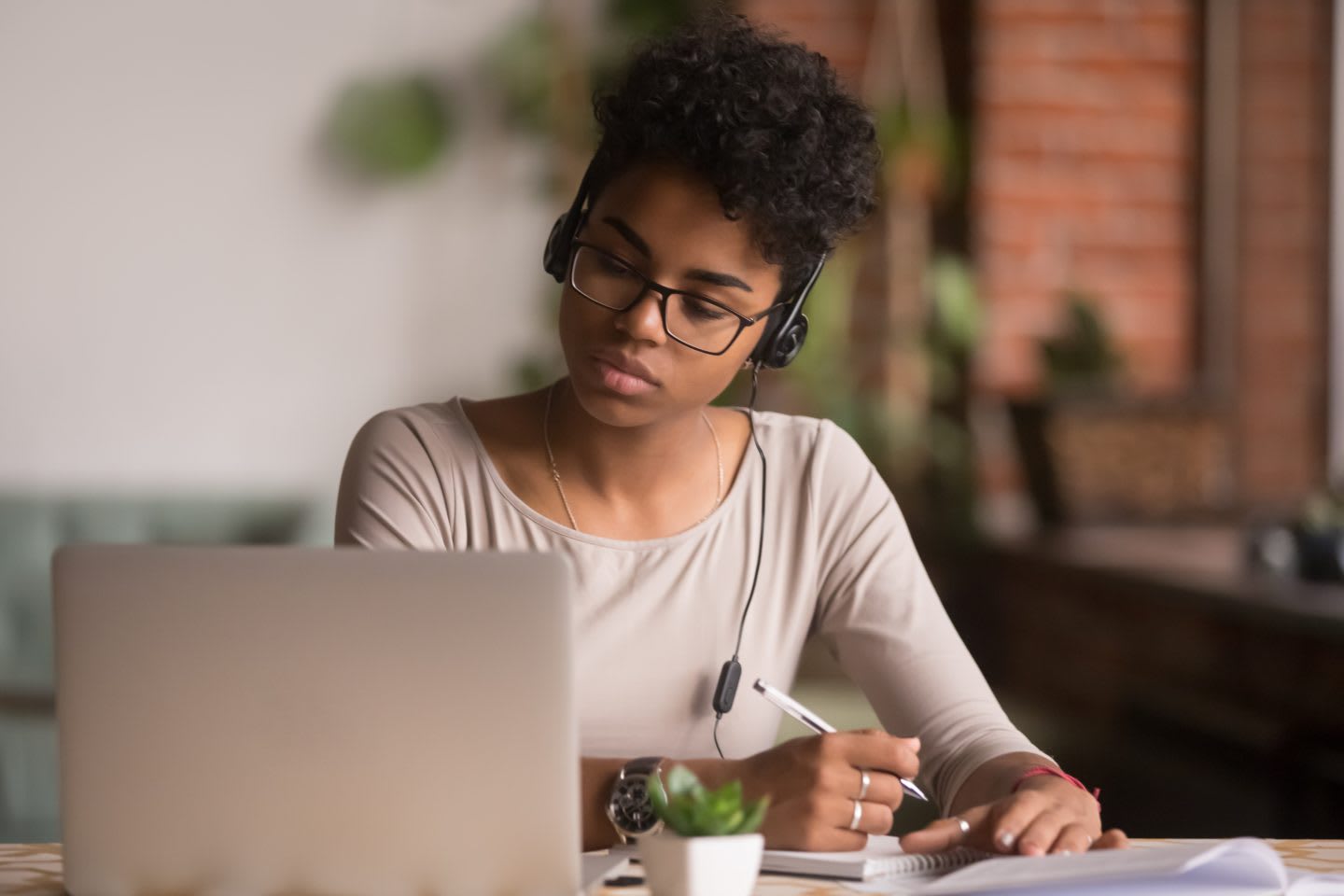 Woman taking notes while listening to a lecture in front of a laptop, studying, learning, development, girl, focus