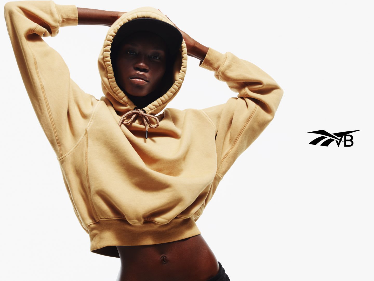 Black model wearing VB x Reebok cropped yellow hoodie from streetwear collection, Victoria Beckham, Reebok, collaboration, fashion
