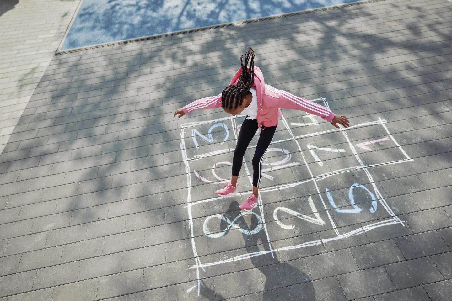 Girl playing in the playground with numbers drawn in chalk on the ground, adidas, sports, movement, apparel