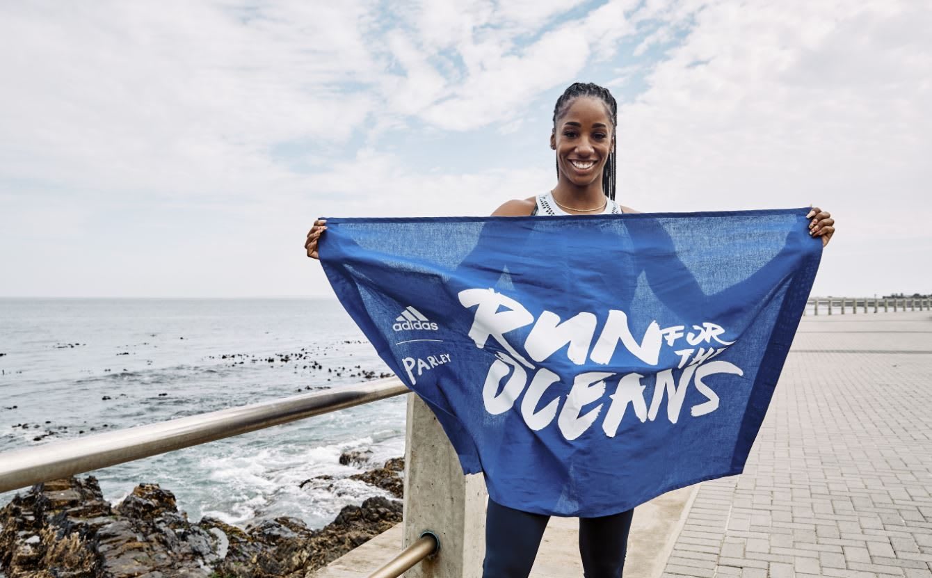 Woman holding Run For The Oceans flag in front of ocean, adidas, sustainability, plastic, waste, sports, purpose, GamePlan A
