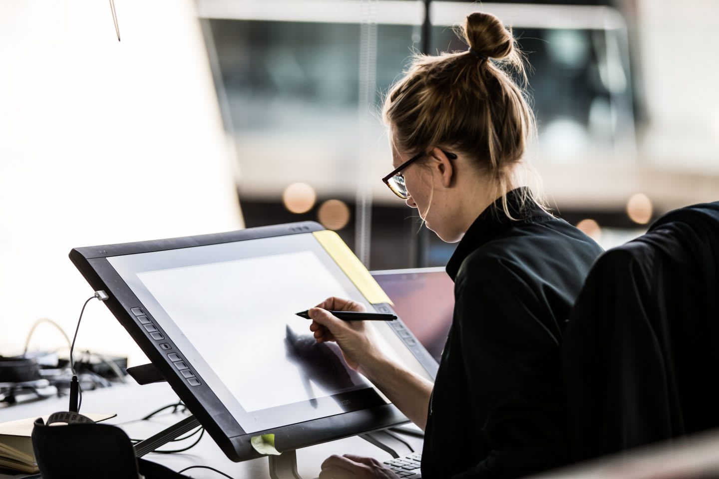 Blonde woman drawing on a digital sketchpad in an office, employee, design, adidas, work, creativity, digital
