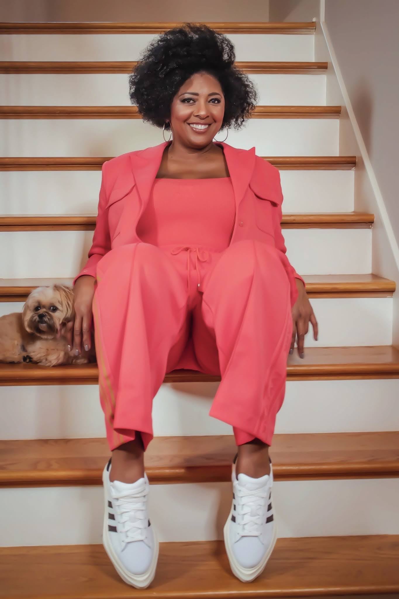 Woman wearing a pink suit sitting on stairs smiling, Vicky Free, marketing, adidas, employee, leadership, leaders, women