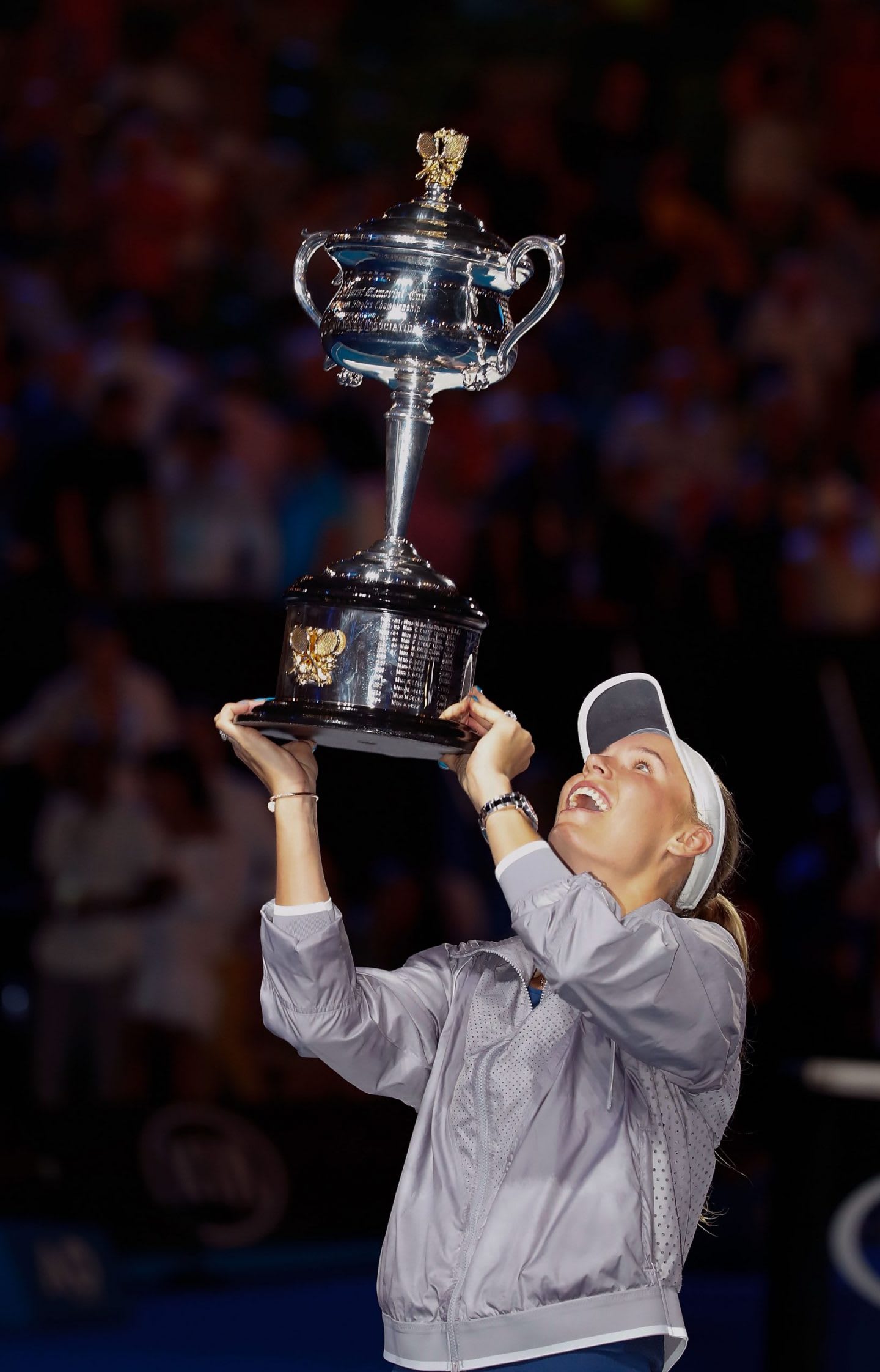 Woman wearing grey tennis outfit holding silver trophy during celebration, Caroline Wozniacki, tennis, player, Danish, athlete, Australia, Melbourne, winner
