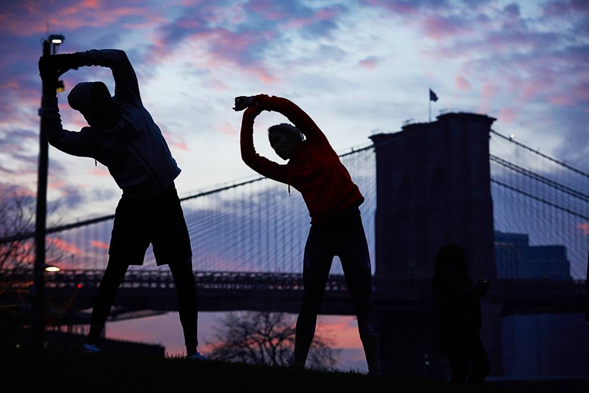 two runners stretching in front of a bridge motivating coach how to clear the hurdle