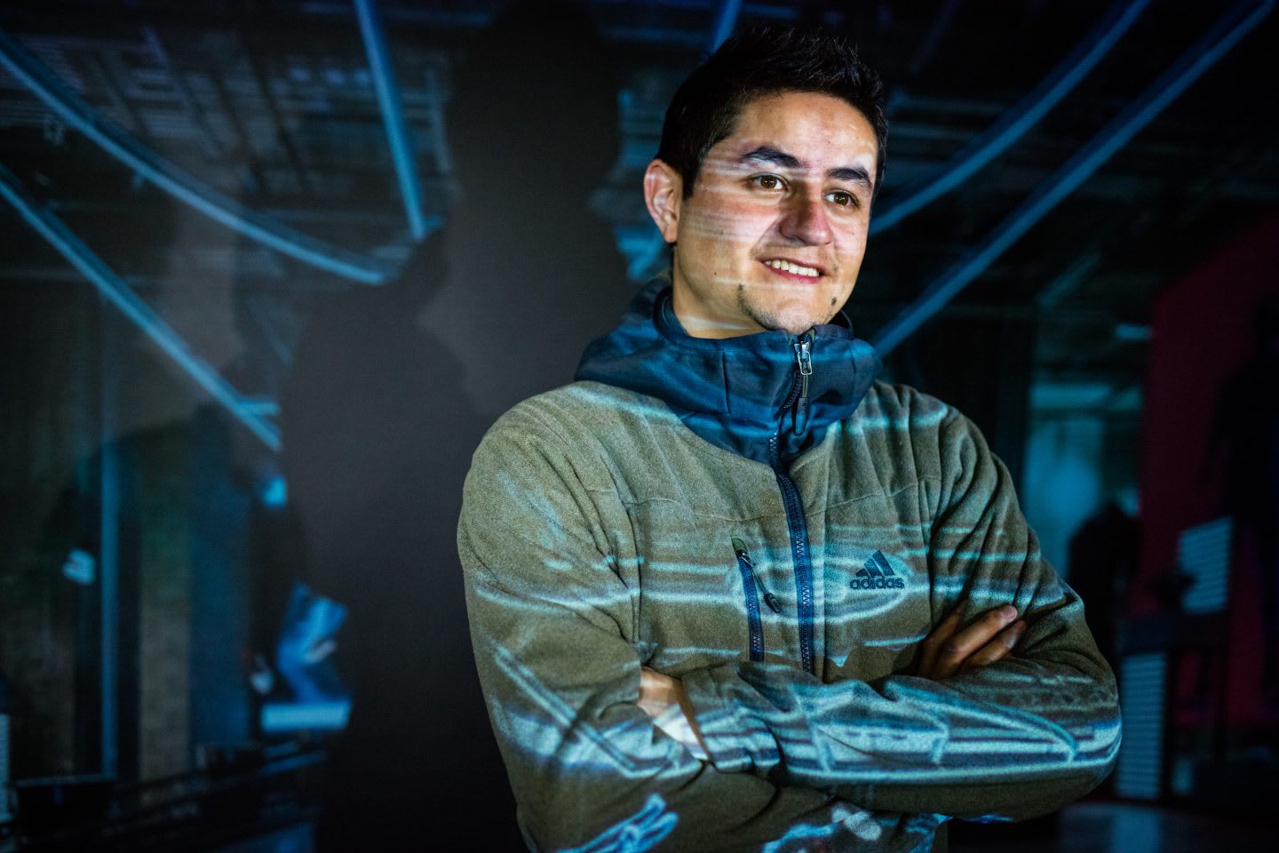Man with crossed arms smiling with a projection behind him