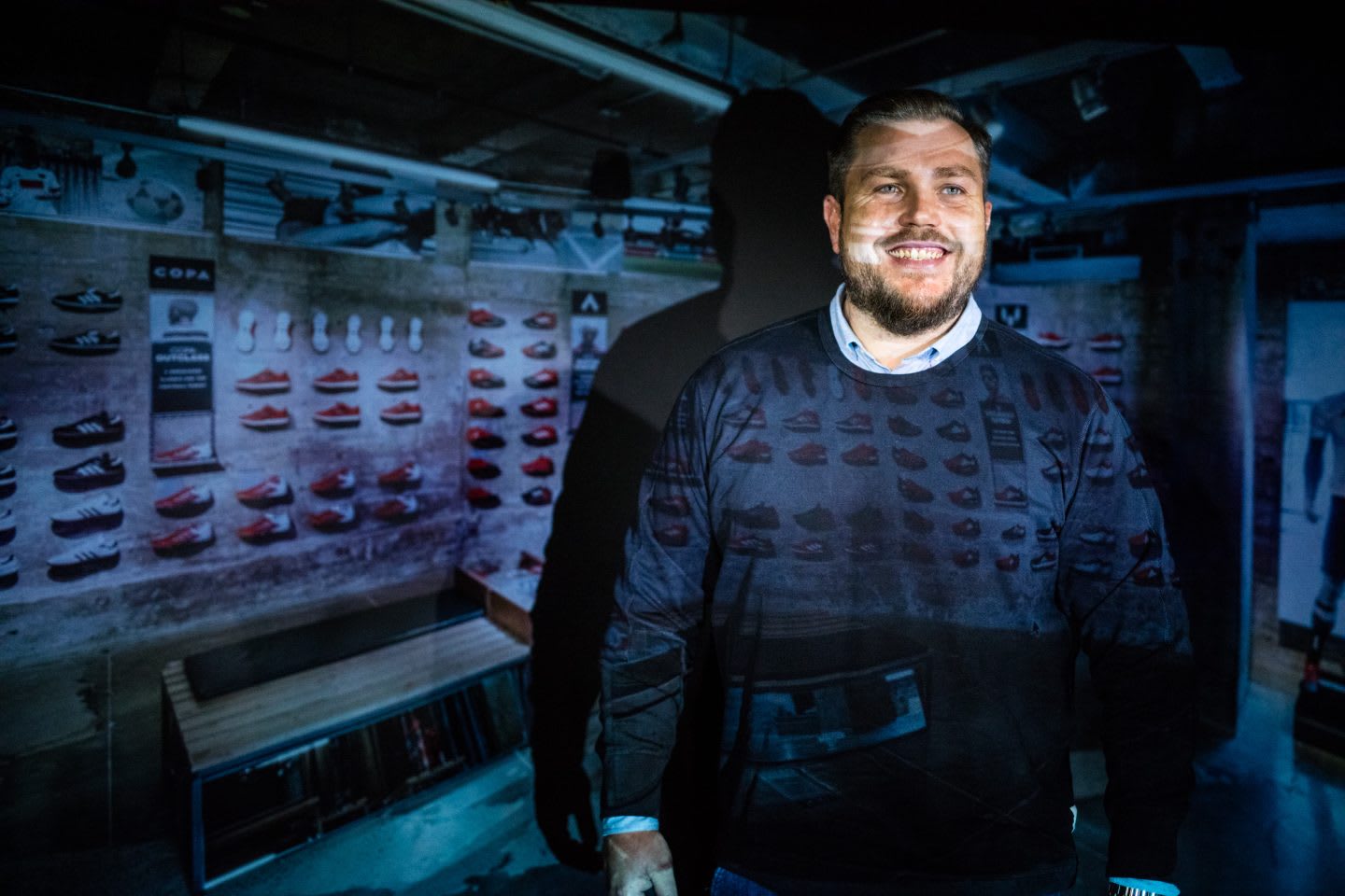 Man smiling with a projection of shoes behind him