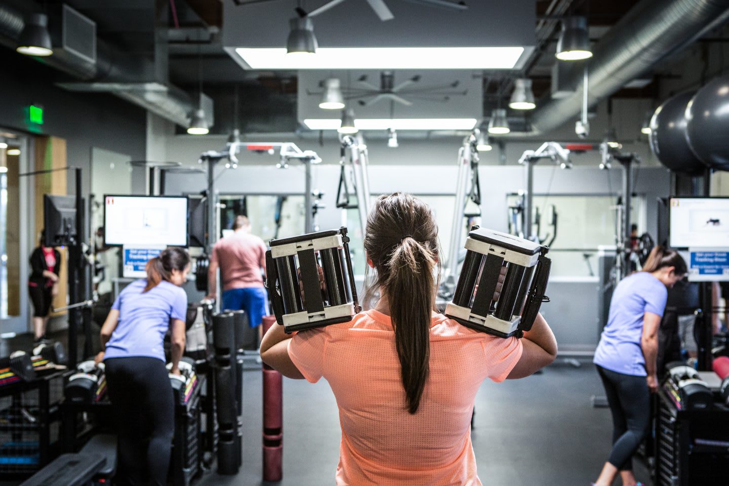 woman with powerblocks in gym-exos-short-term-goals-long-term-success