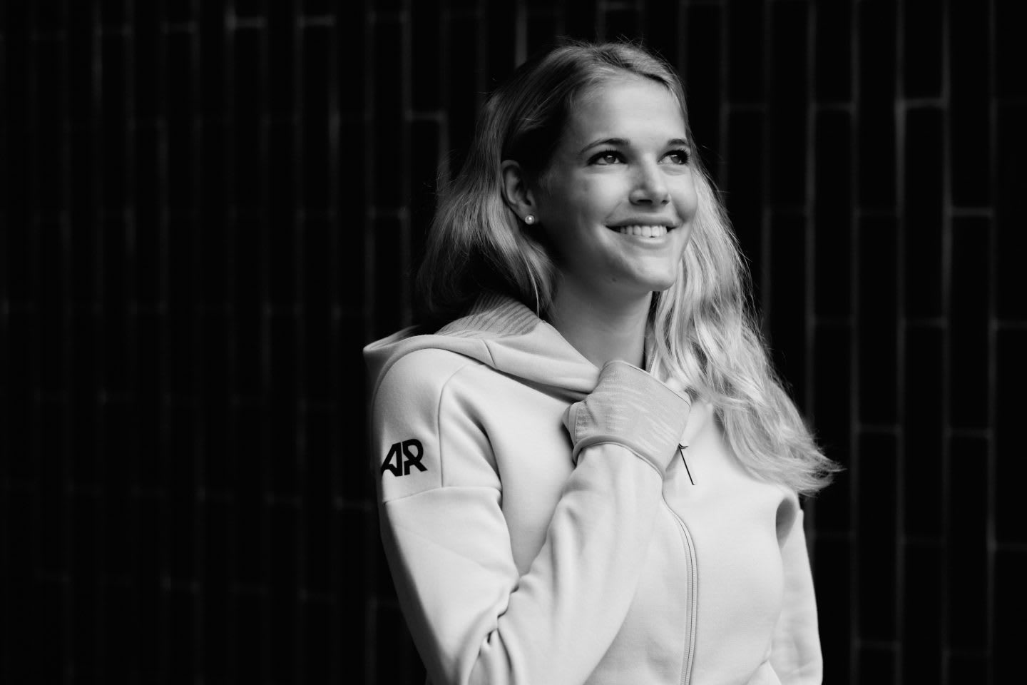 Back and white picture, girl smiling in front of a black background and wearing an adidas Runners track top, Simone Luder_adidas Runners_GamePlan A