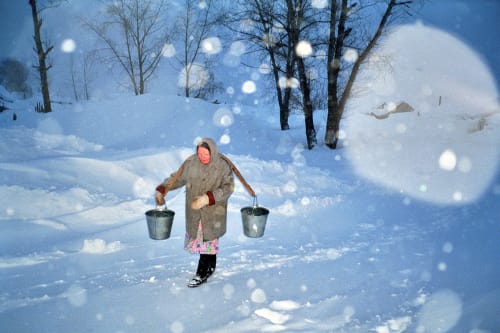 Woman Carrying Water Buckets in the Snow — photograph by John Peter Askew