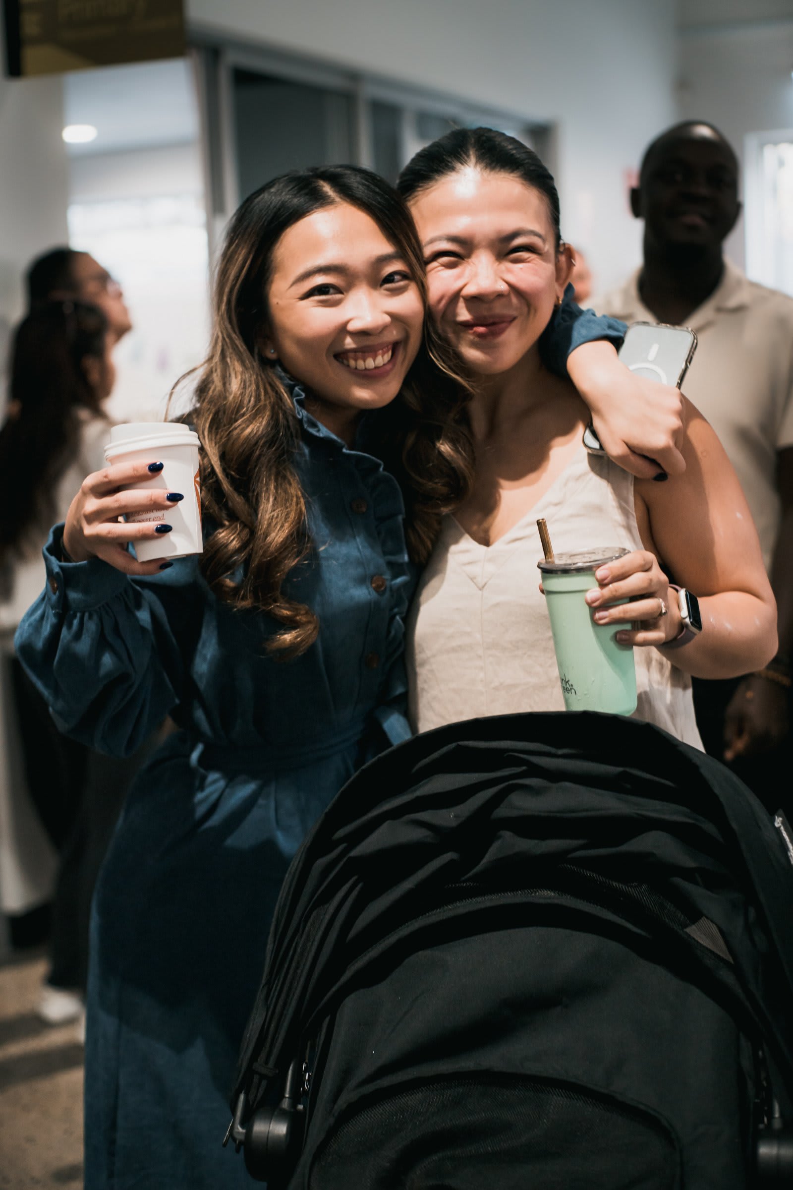 Two City Women Hugging Smiling Holding Coffee