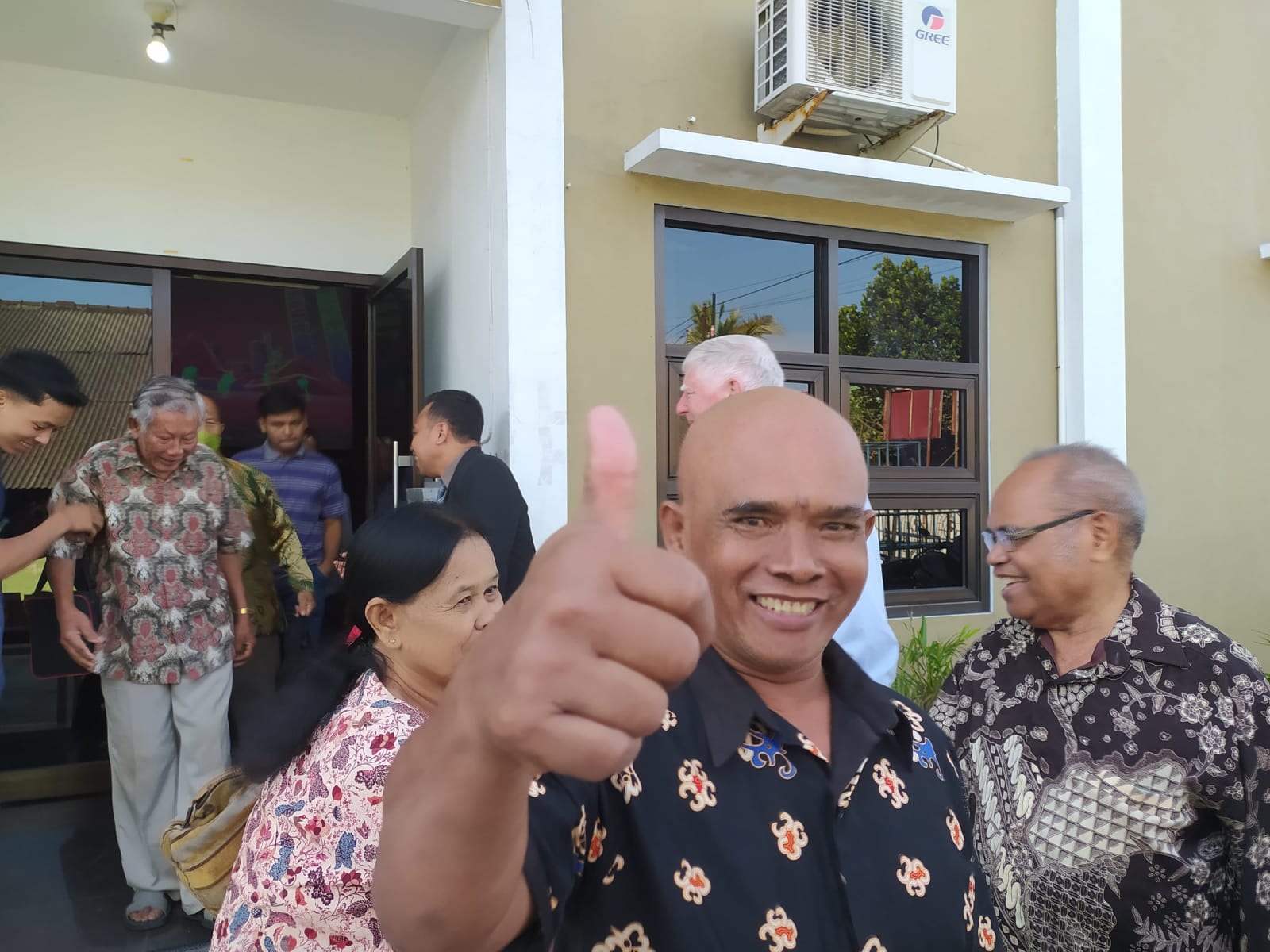 Cemani man outside of church giving thumbs up smiling