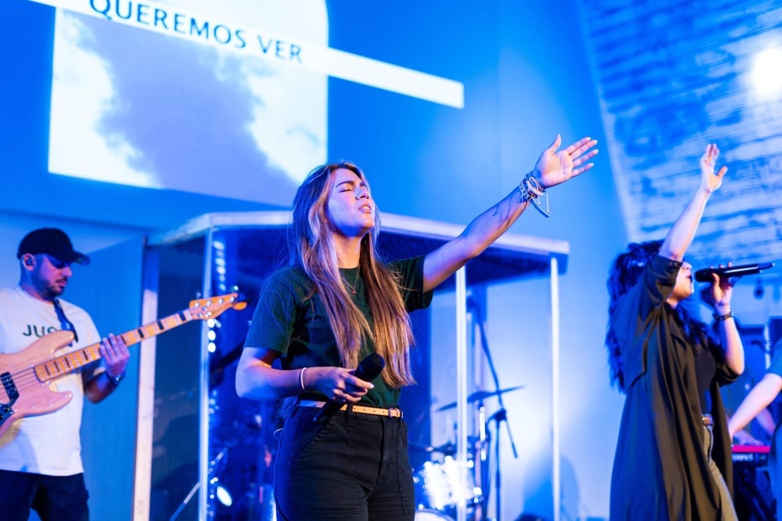 A worship singer with arms raised on stage / duluth
