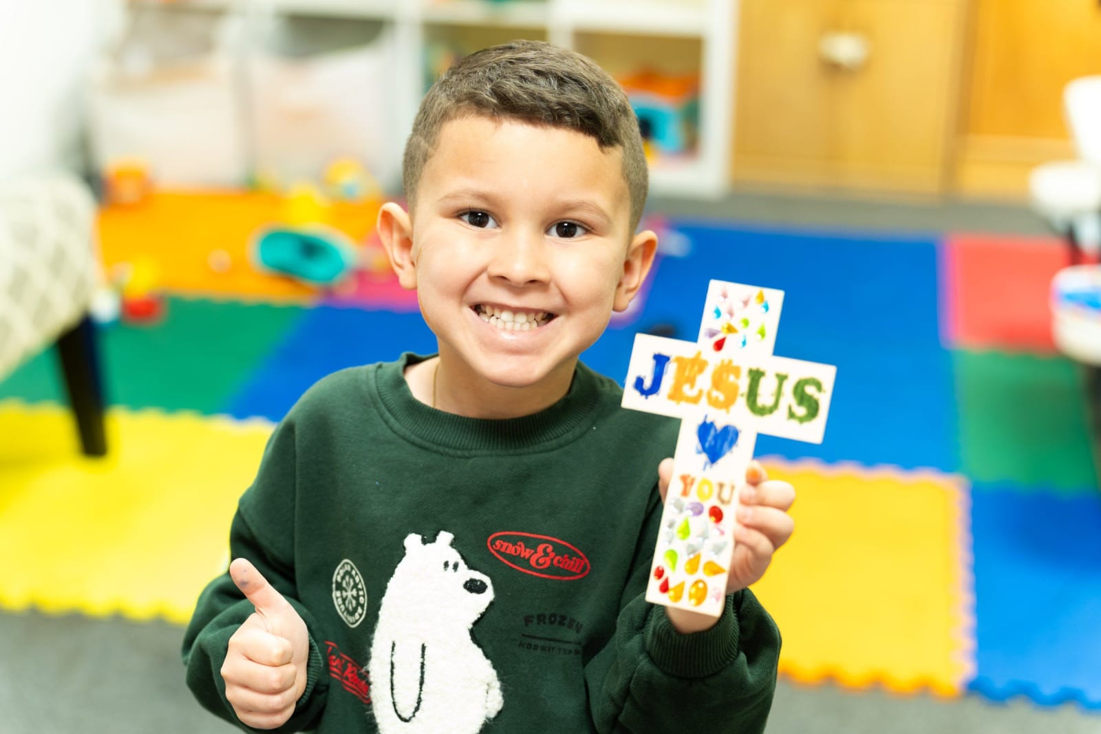A smiling boy holding a craft cross / duluth