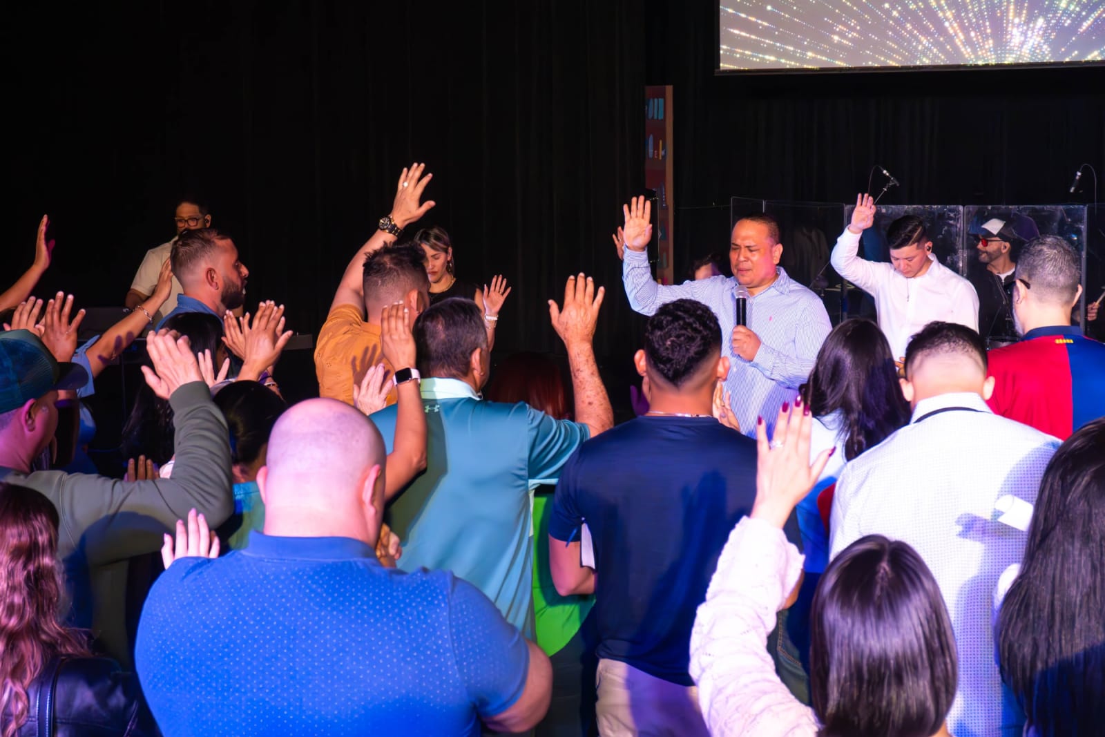 Speaker leading a group in prayer with raised hands / grayson