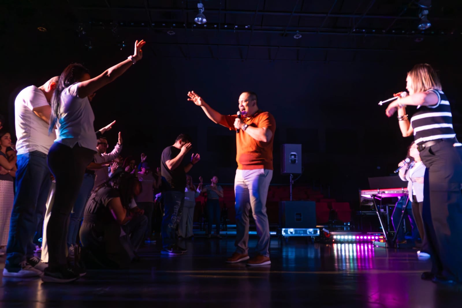 Worship leader on stage with congregation / grayson