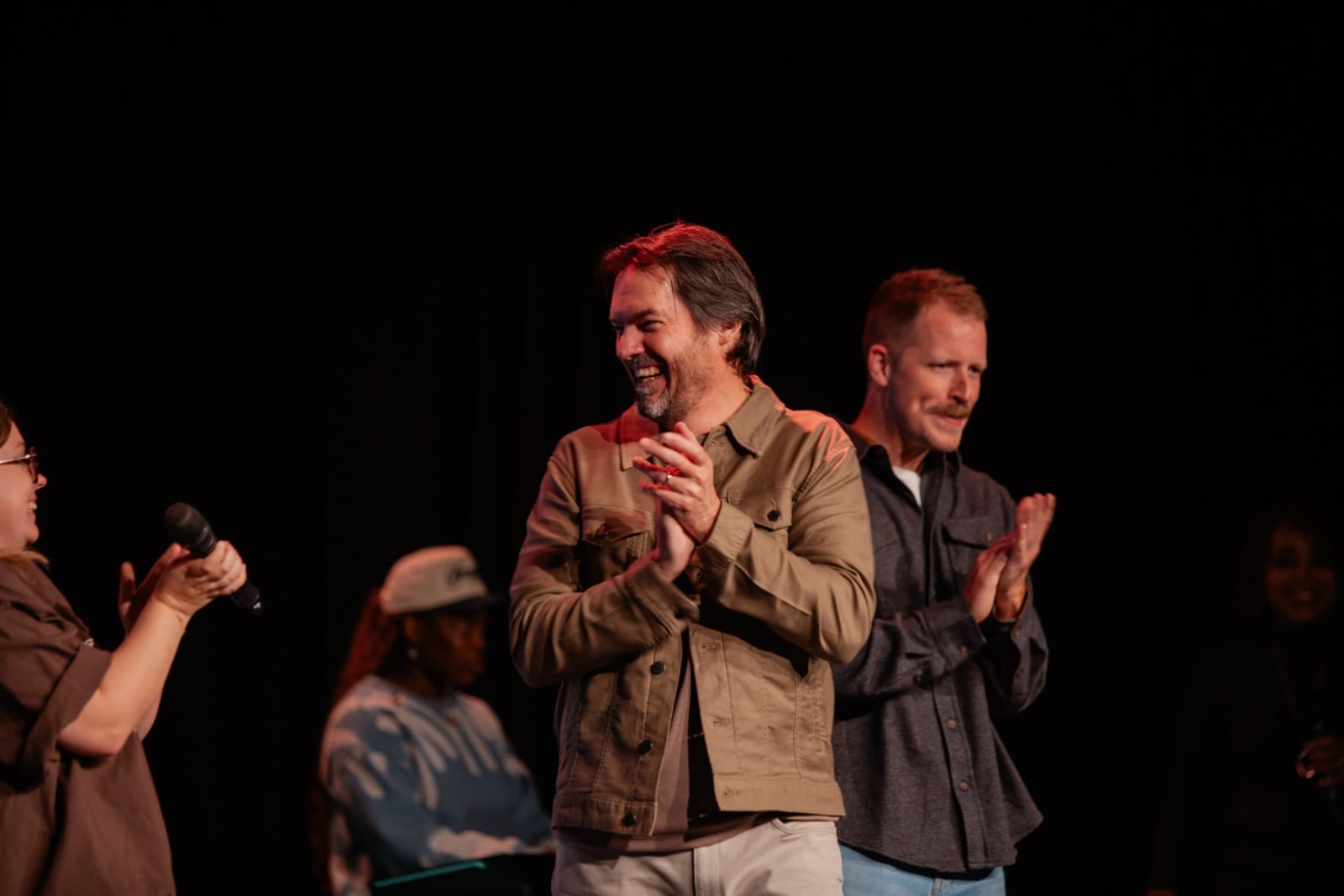 two men smiling and clapping on stage / gwinnett
