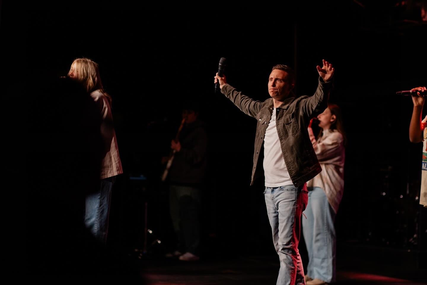 worship leaders singing with hands raised on stage / gwinnett