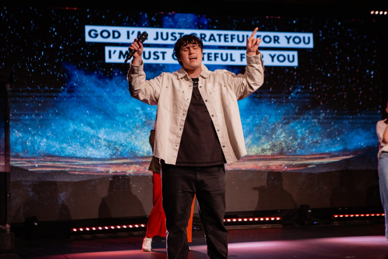 young adult man singing and pointing up / gwinnett + stage