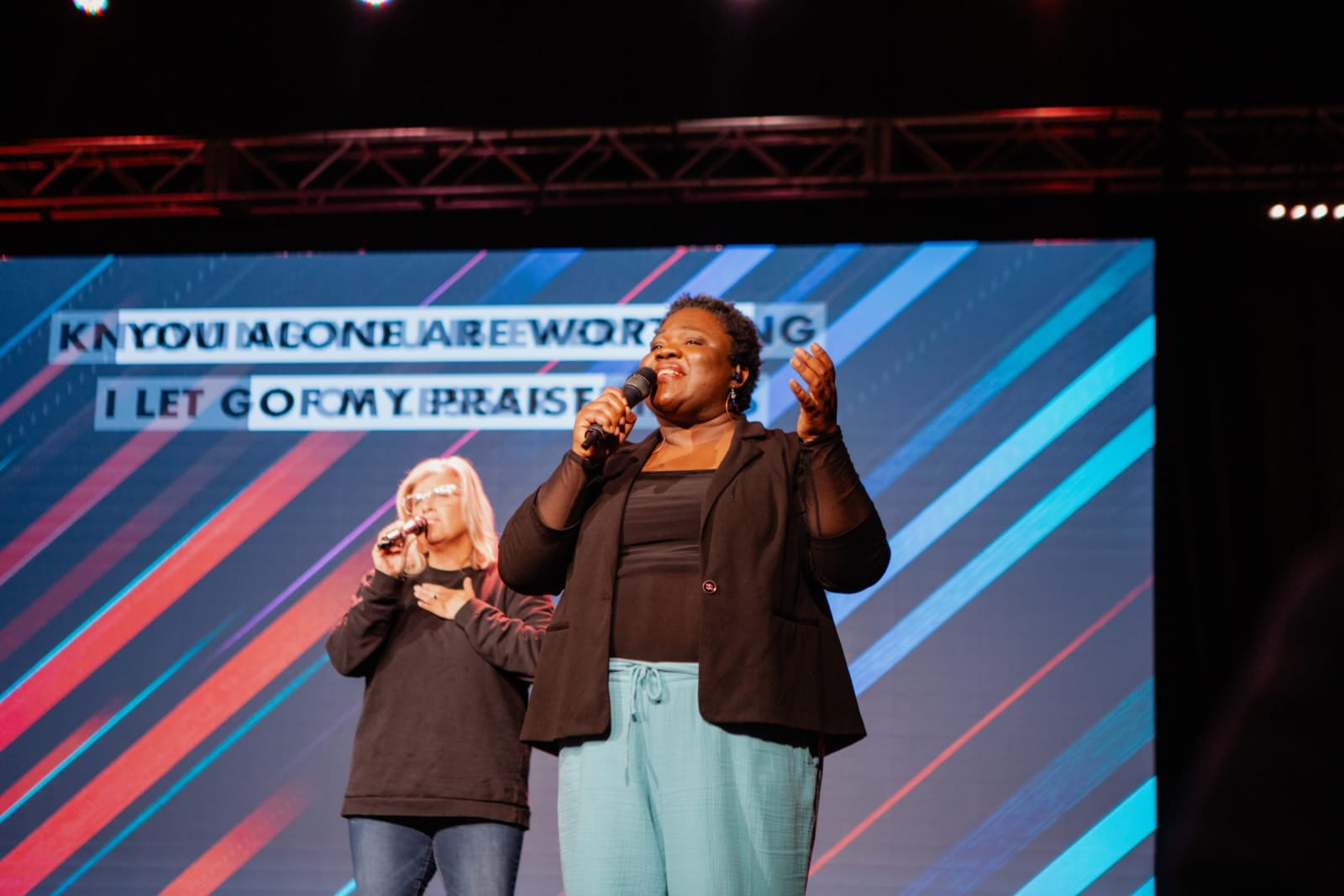 Woman Singing with mic raised to mouth  / Gwinnett + Stage