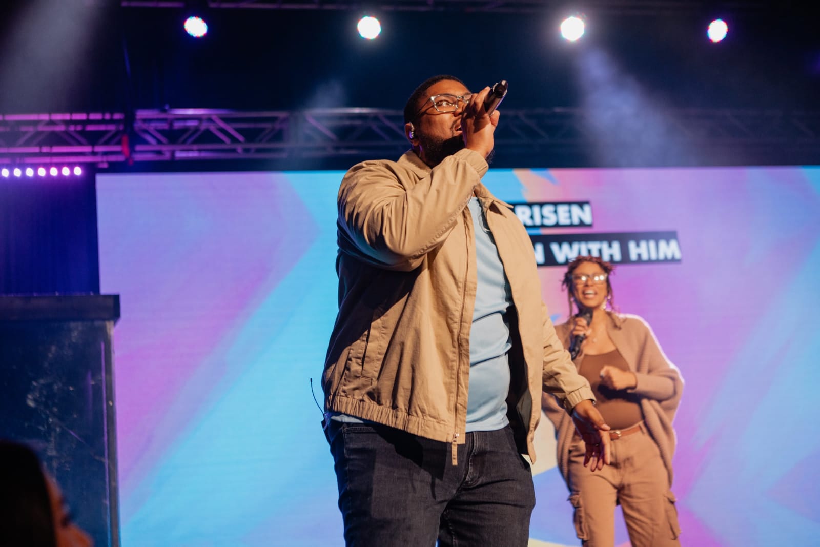 Man Singing with mic raised to mouth  / Gwinnett + Stage