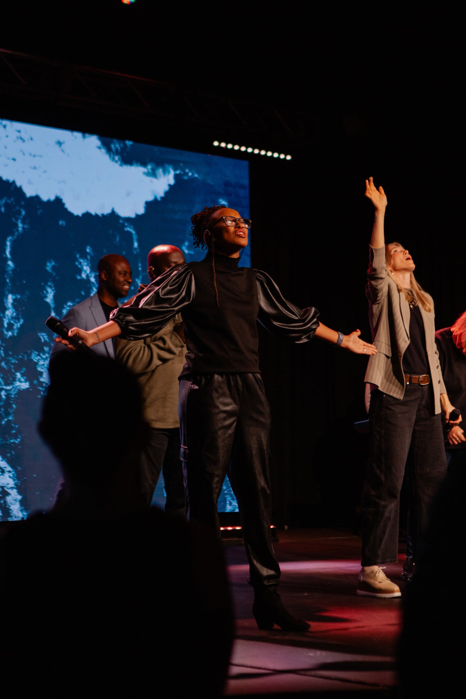 Adult women worshipping with arms stretched out  / gwinnett + stage