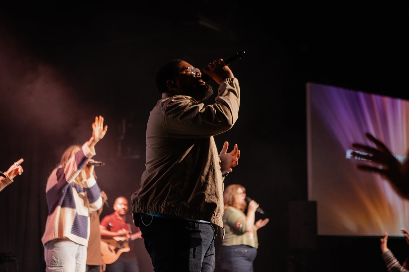 Man Singing with mic raised to mouth  / Gwinnett + Stage