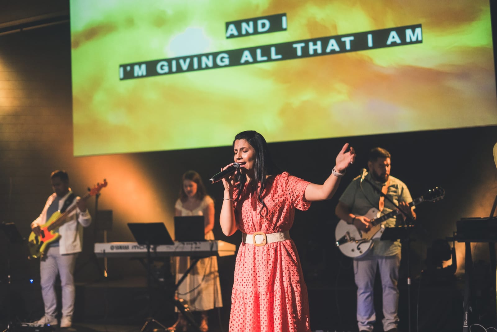 female worship singer singing with band on stage / kennesaw