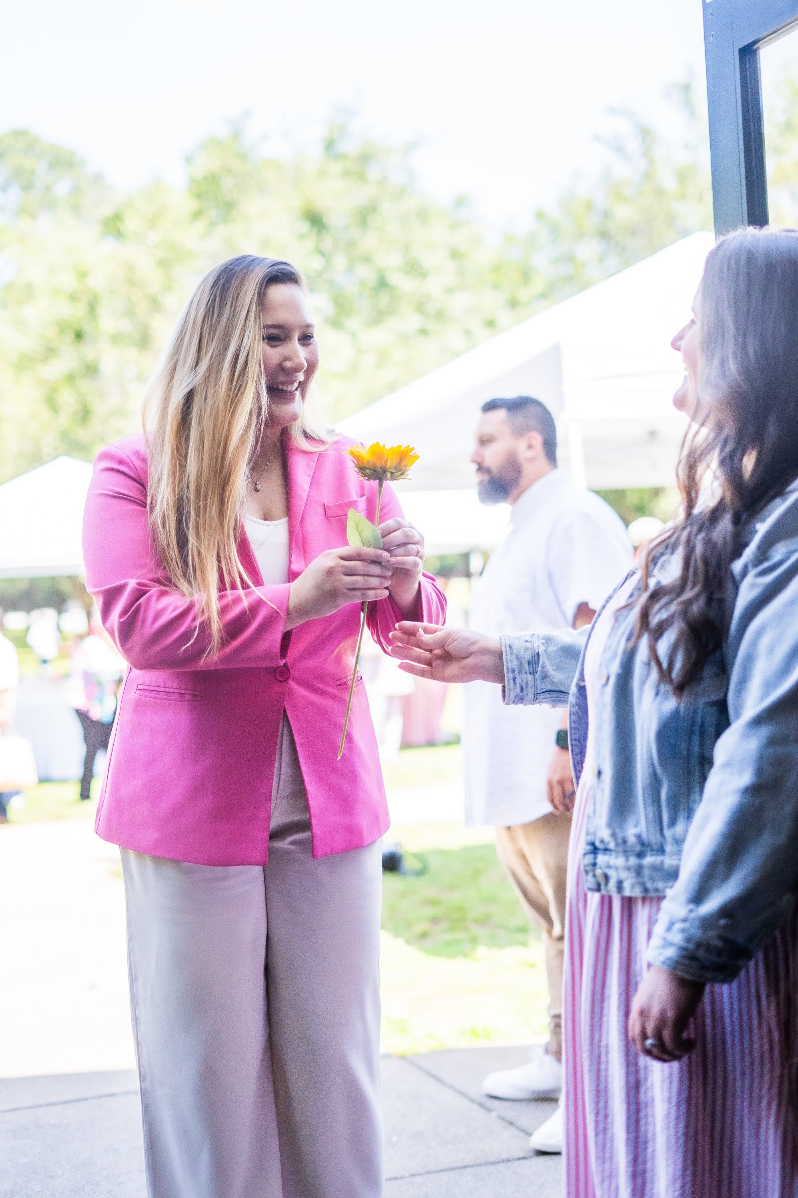 woman handing a sunflower at outdoor event / kennesaw