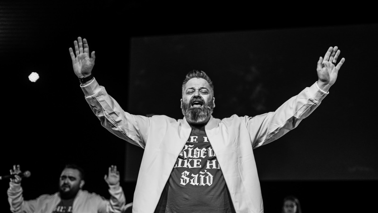 male worship leader with arms raised black and white photo / kennesaw