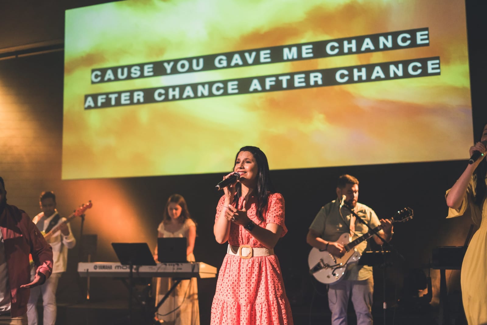 female worship singer singing with band on stage / kennesaw