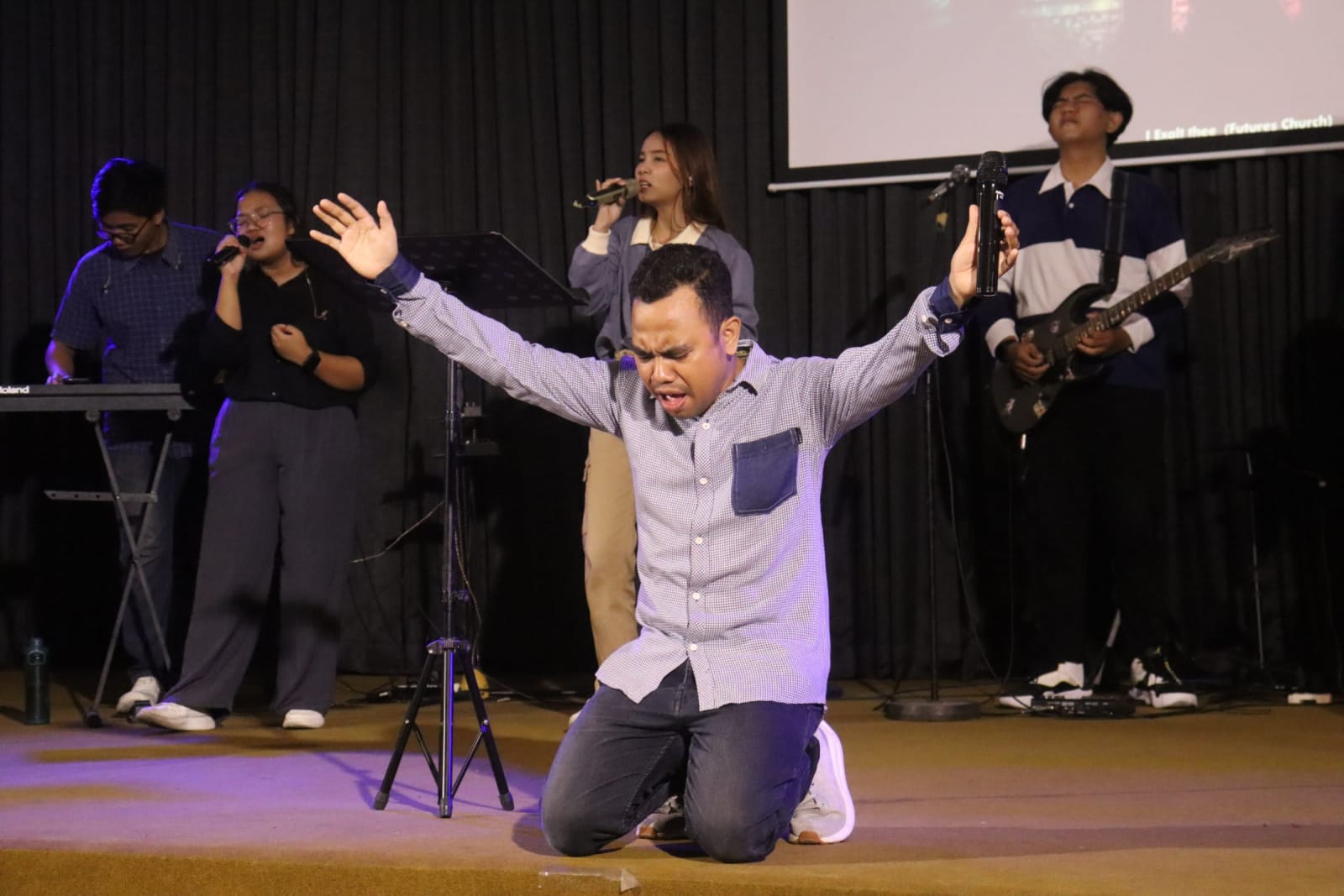 Man kneeling in worship on stage at Solo campus Futures Church Sunday service