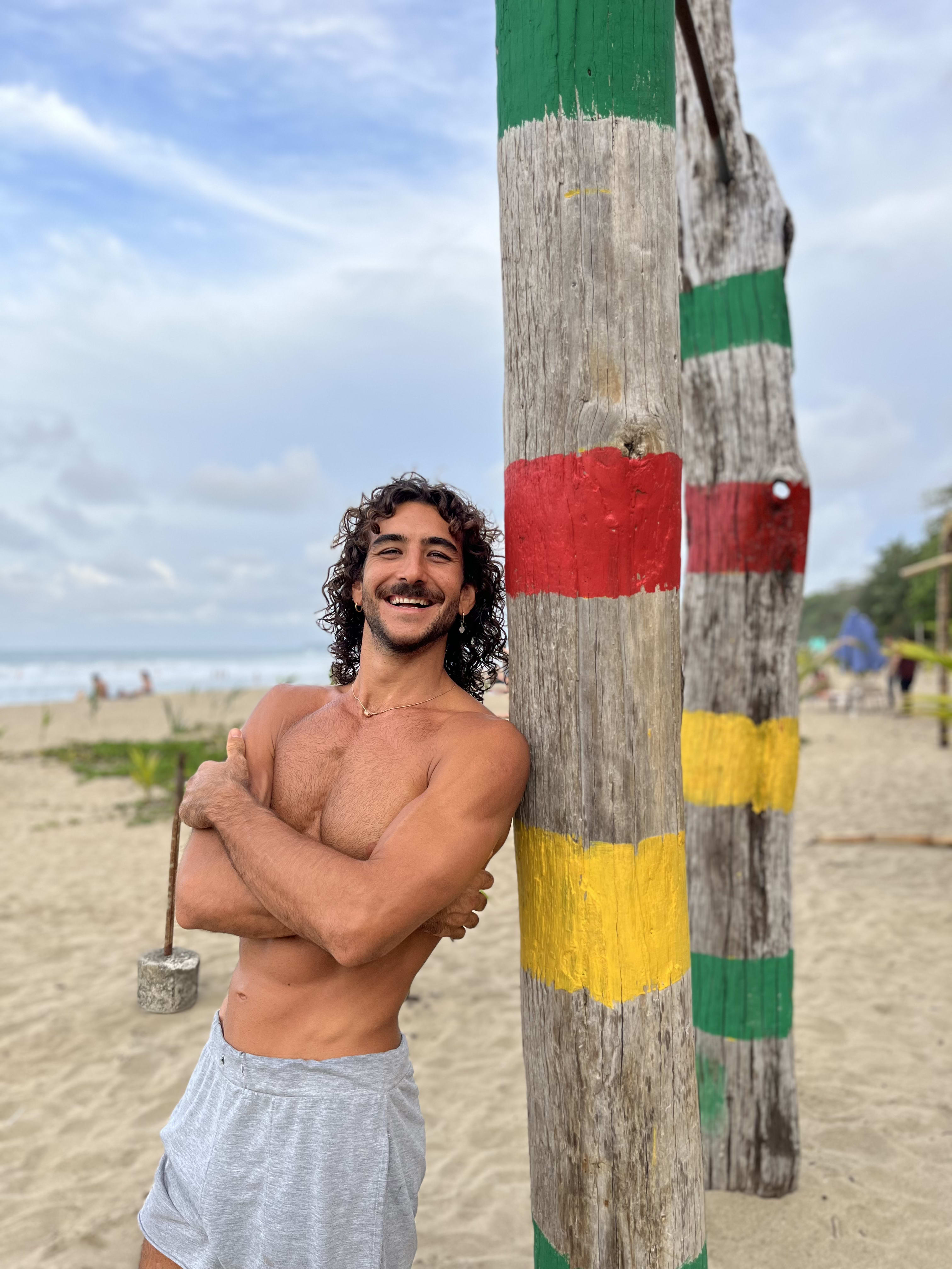 Coach de movimiento sonriendo a cámara en un gimnasio al aire libre junto a la playa