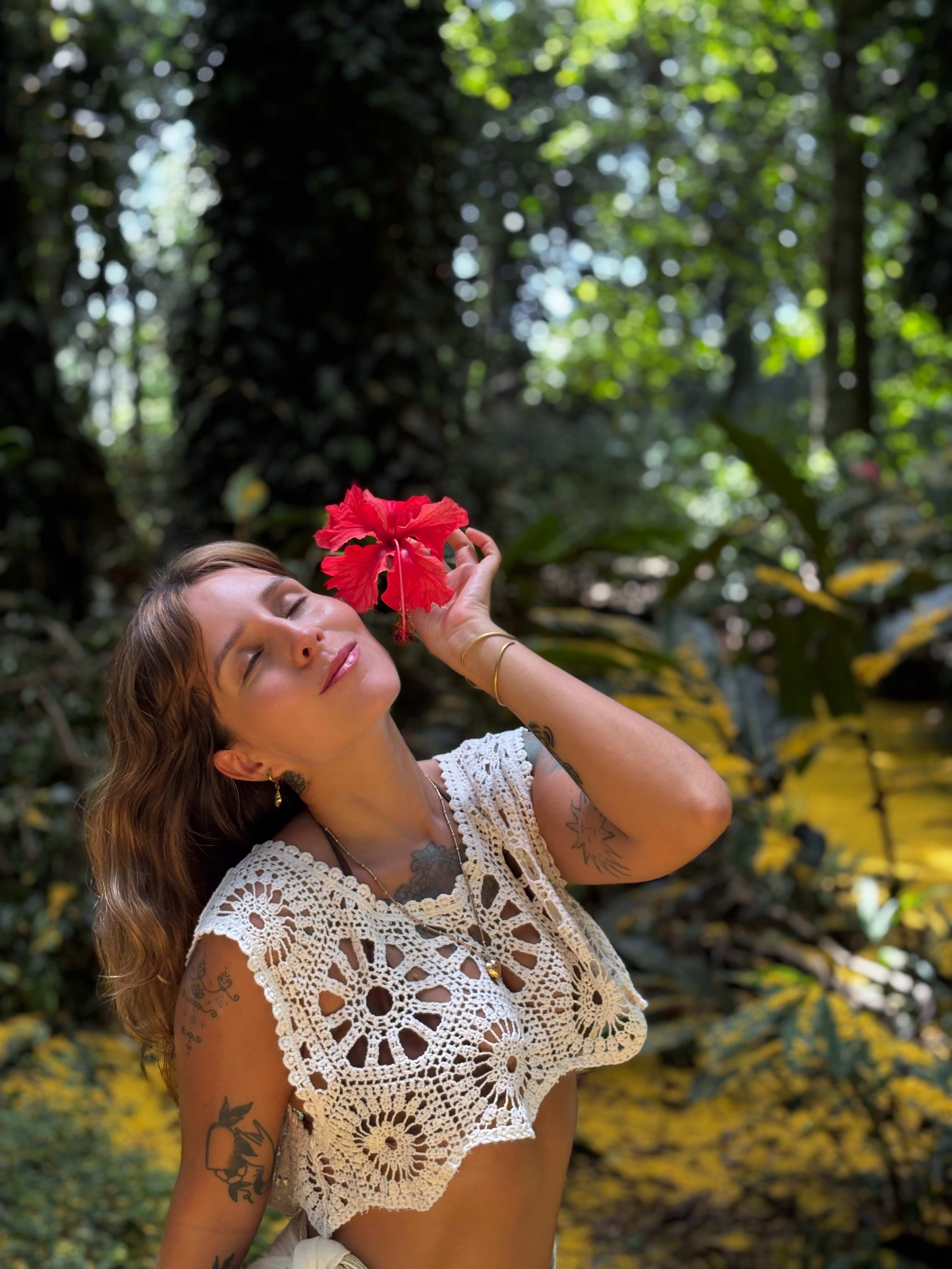 Psychologist Luz Aguiar in ceremonial attire on a wooden balcony overlooking a tropical forest