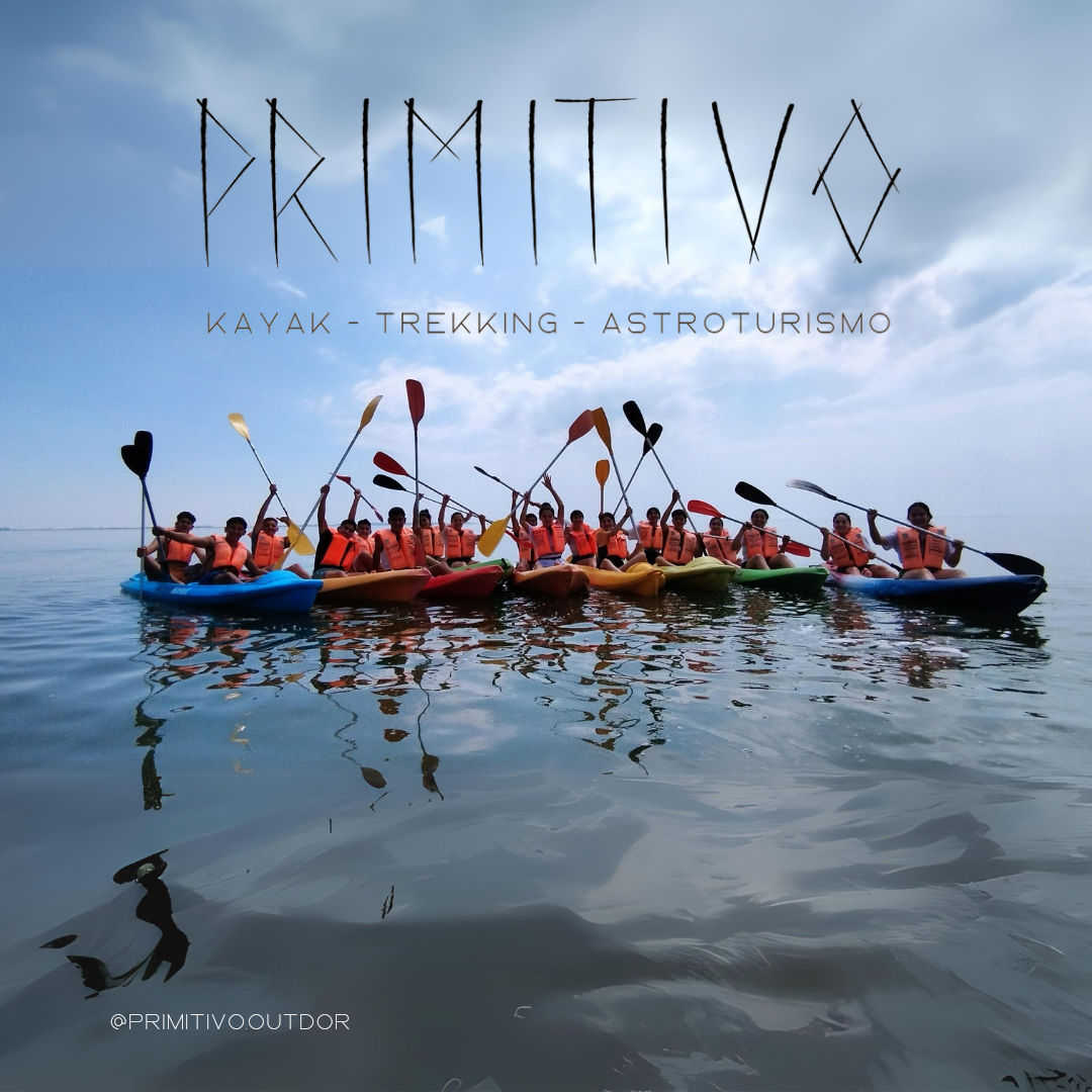 Grupo de turistas en kayaks sobre una gran laguna alzando los brazos y enseñando los remos. 