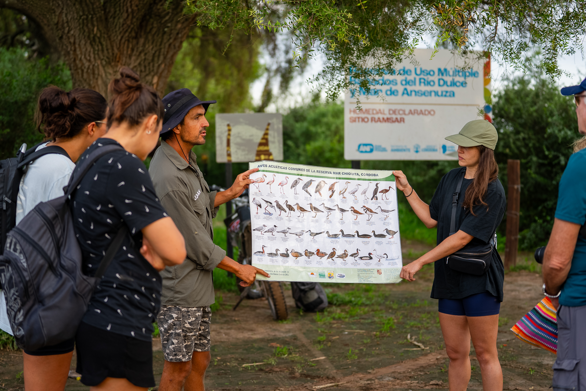 Biólogo enseñando especies de aves a grupo de turistas en un bosque nativo.