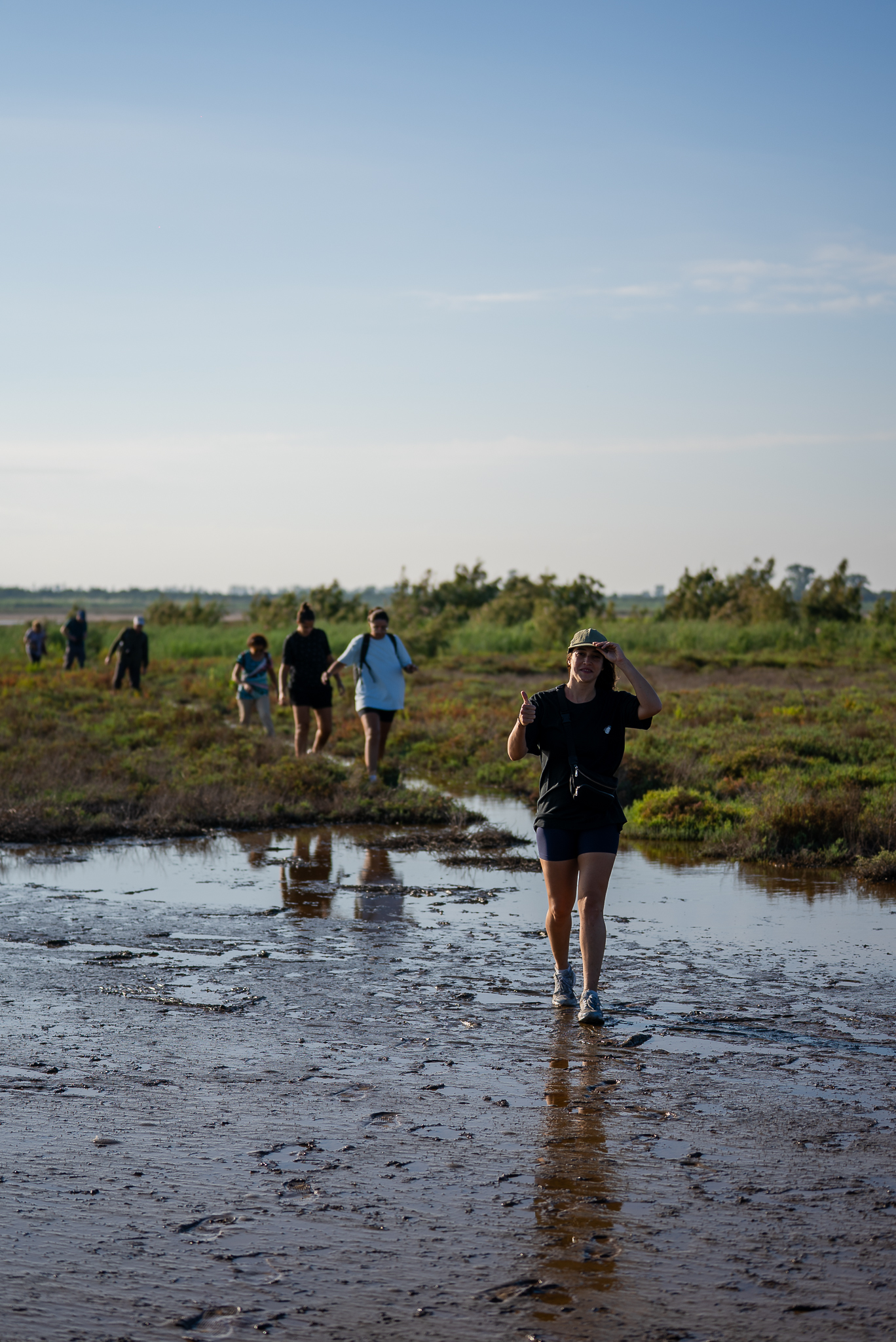 Caminata grupal por senderos de lodo y vegetación nativa.