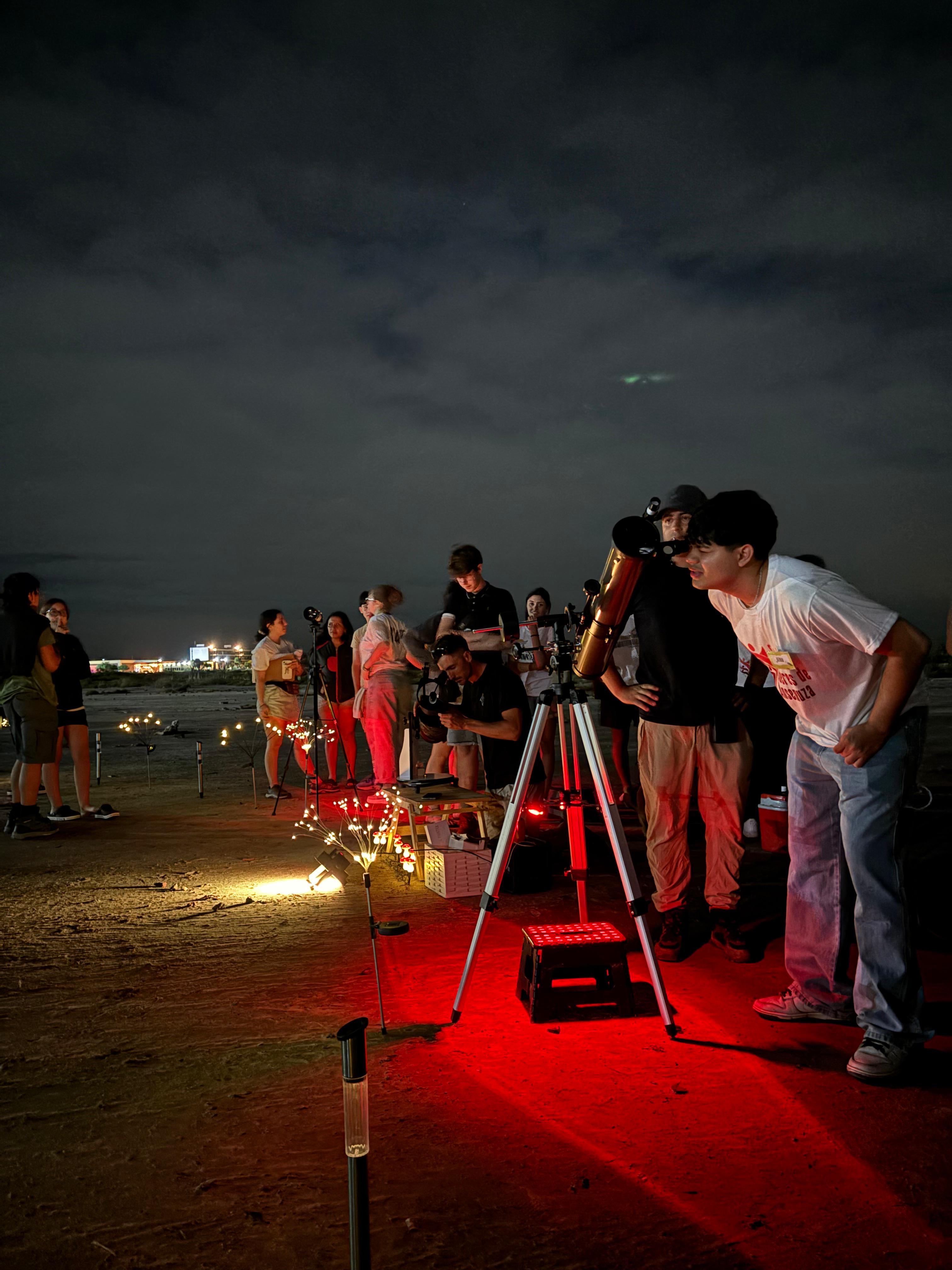 Contingente escolar observando el cielo nocturno con telescopios.