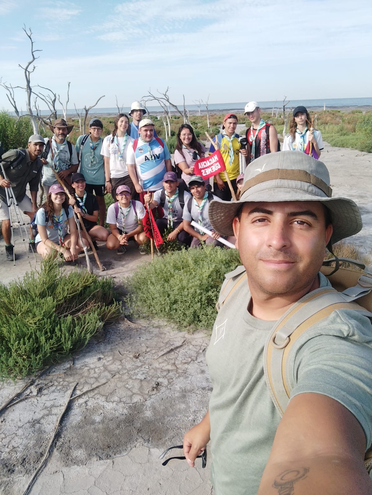Guía tomándose un selfie con grupo de turistas detrás en un paisaje natural con la laguna de fondo
