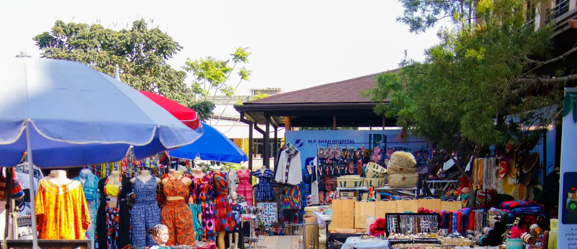 Market stalls under blue and red umbrellas at The Hub Karen