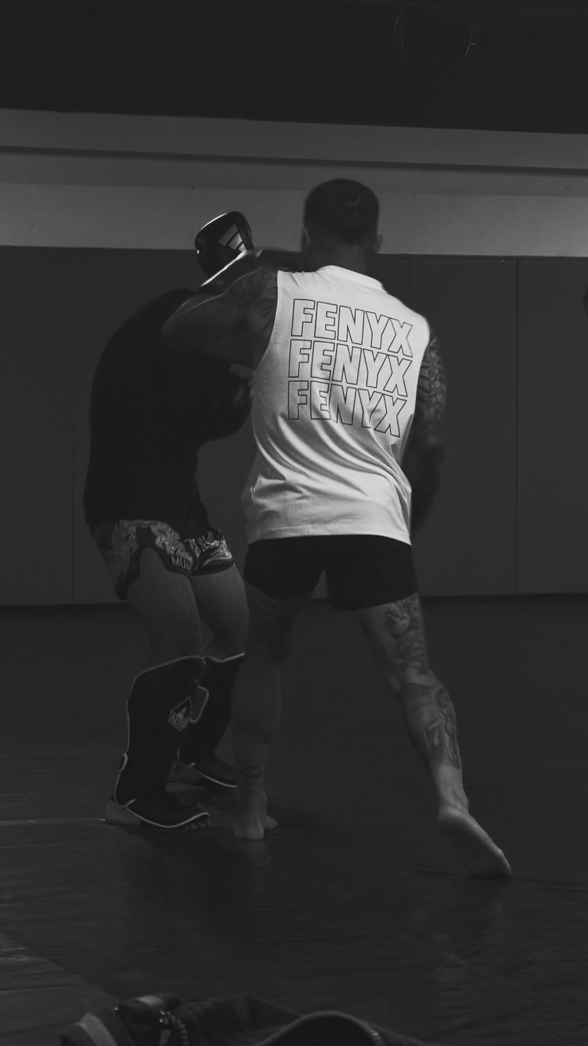 Two athletes sparring in low-light gym wearing FENYX apparel