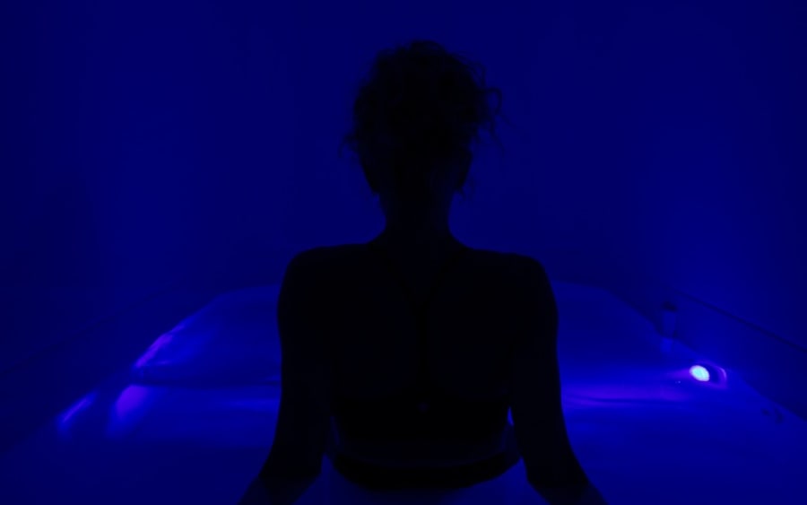 Guest sitting up in the float pod under blue light