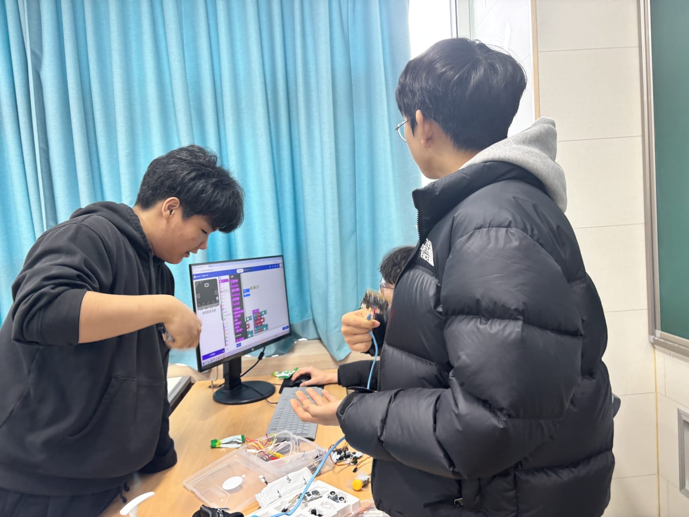 강사가 학생들 앞에서 마이크로비트 피지컬코딩 수업을 진행하고 있다.