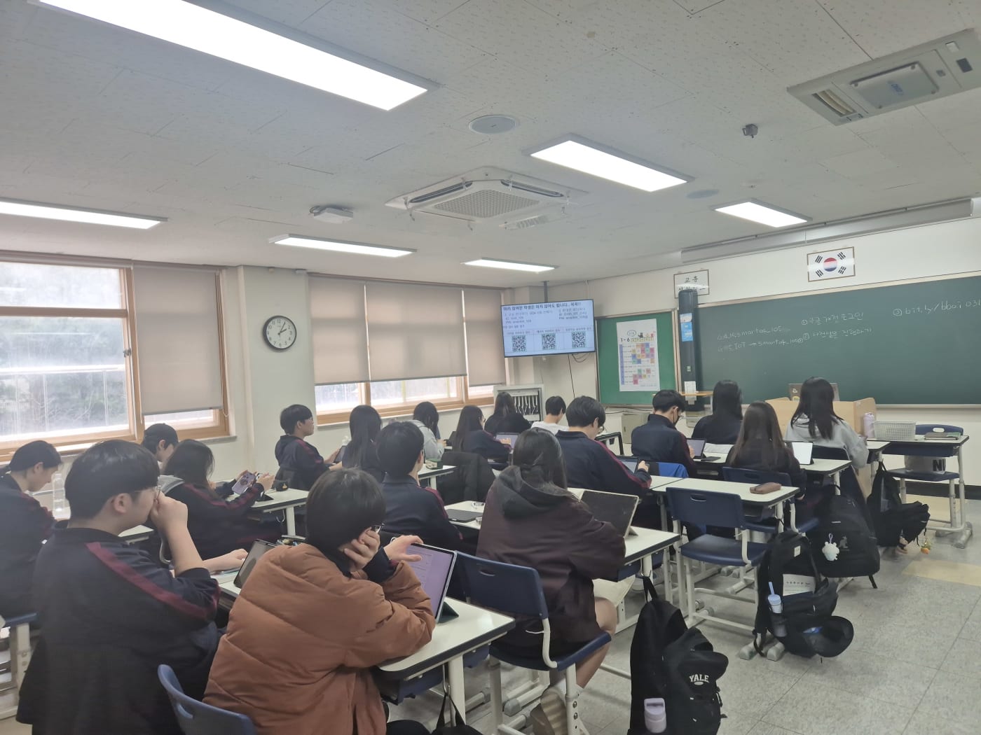 스크린의 QR 코드를 통해 실습에 참여하며 디지털 도구를 적극 활용하는 학생들